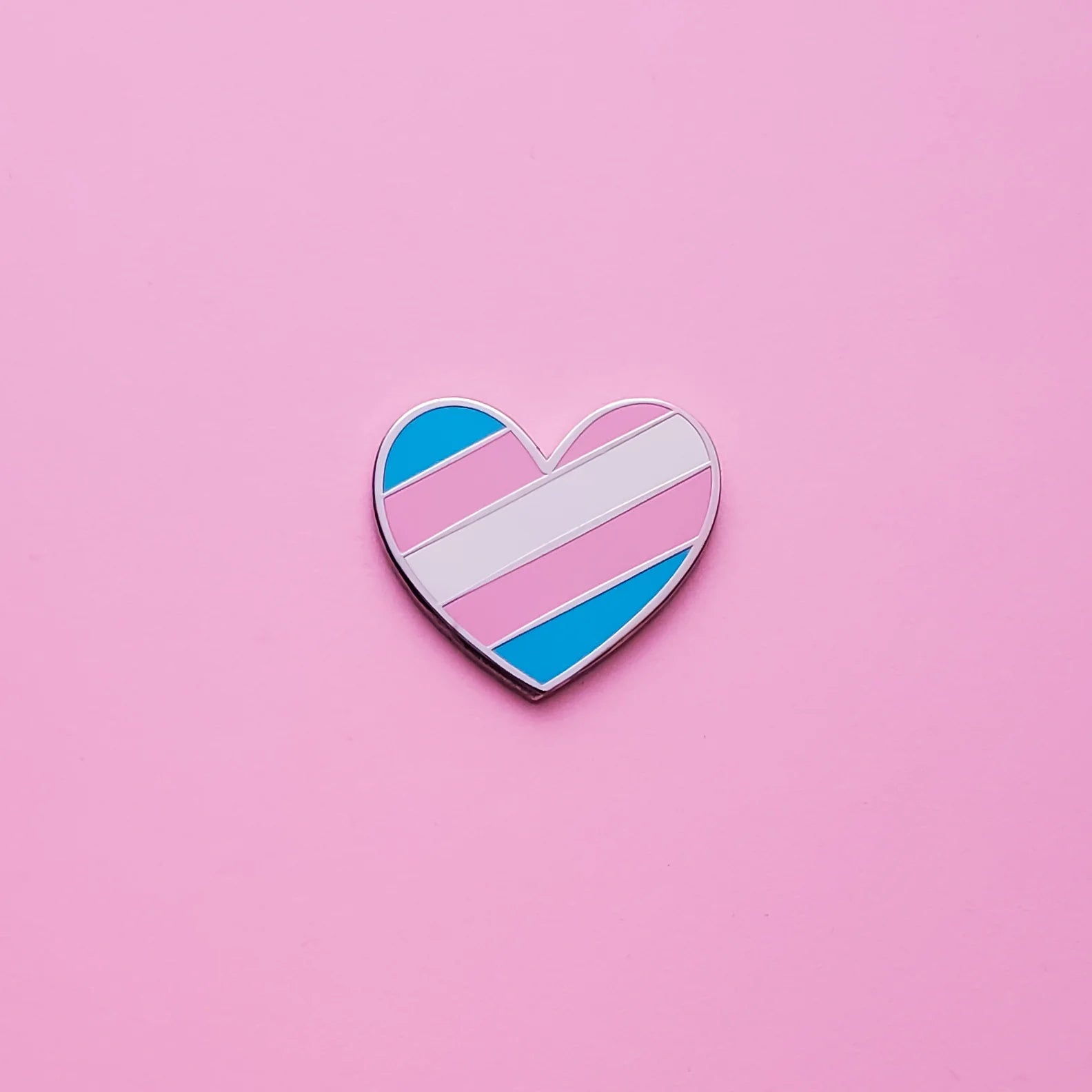 Trans Heart Pin by trans ally Little Rainbow Paper Co on a pink background