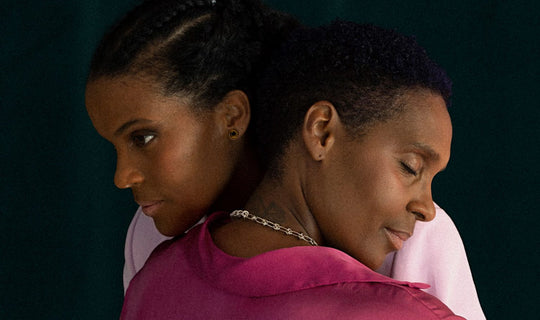 Two people, wearing different shades of pink, hugging each other